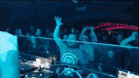 a crowd of people are dancing in a dark room at a club .