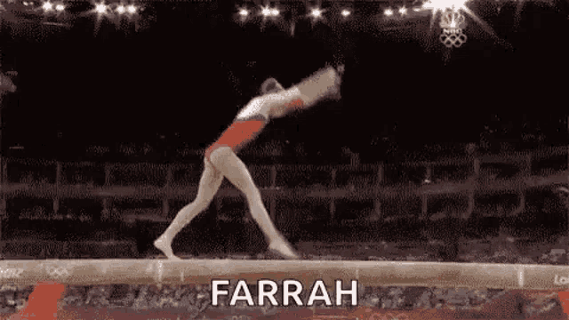 a female gymnast is doing a trick on a balance beam in a stadium .