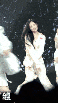 a woman in a white outfit is dancing in front of a sign that says ' ash '