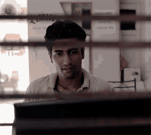 a man in a white shirt is looking at a computer screen