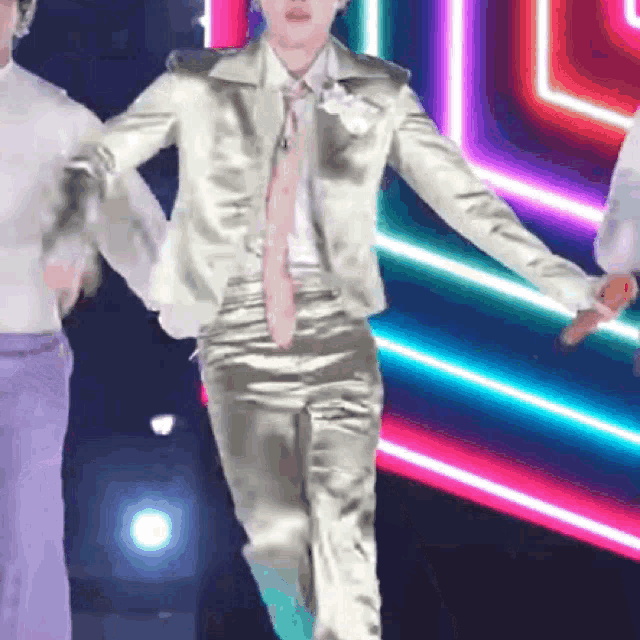 a man in a suit and tie is dancing on a stage in front of neon lights .