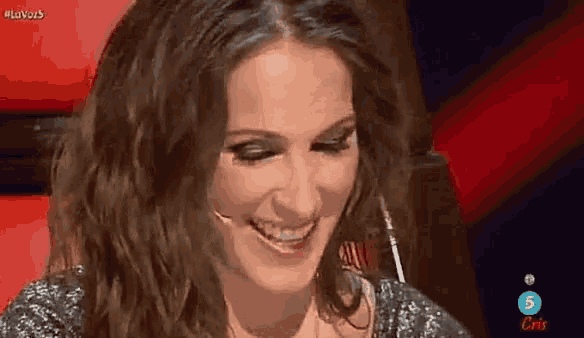 a woman is smiling while sitting in front of a microphone on a red background .