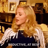 a woman is sitting on a couch with her eyes closed and saying `` reductive , at best '' in a living room .