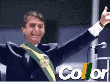 a man in a suit is waving his arms in front of a microphone and the word collar is on the bottom right