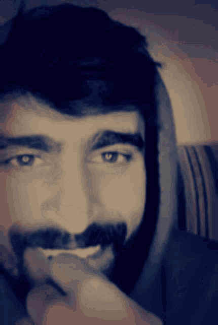 a man with a beard is smiling with his hand on his face