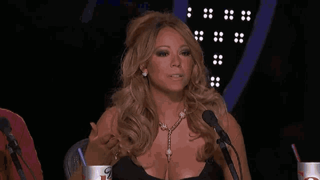 mariah carey is sitting in front of a microphone .
