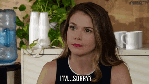 a woman is saying i 'm sorry while sitting in front of a water cooler