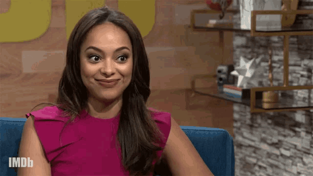a woman in a pink dress is sitting on a blue couch with imdb written on the bottom