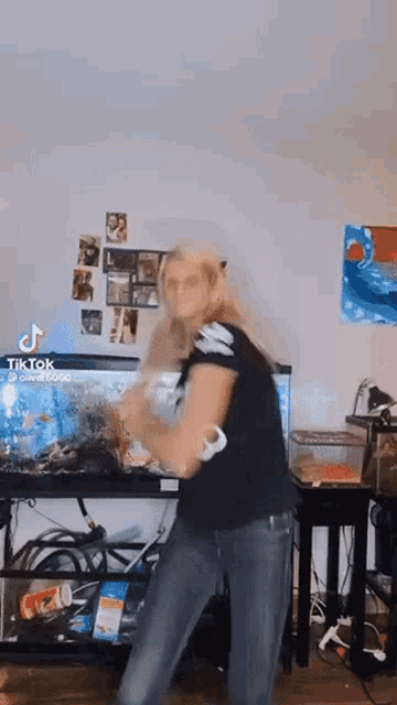 a woman is dancing in front of an aquarium in a room with a tik tok watermark