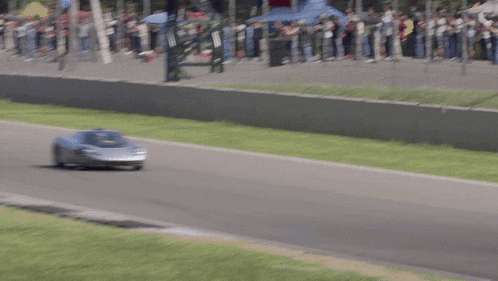 a car is driving down a race track with a red fence behind it
