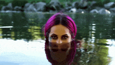 a woman with pink hair is standing in a body of water