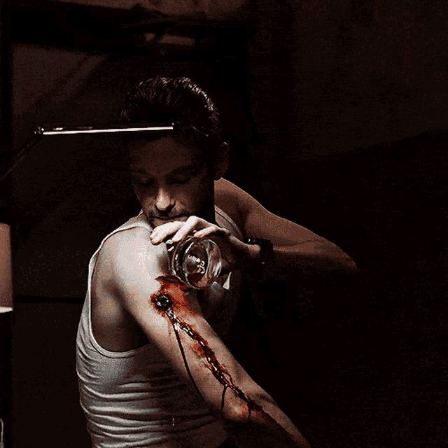 a man in a white tank top has a bloody arm
