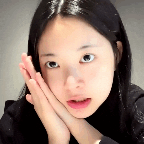 a close up of a woman 's face with her hands on her chin