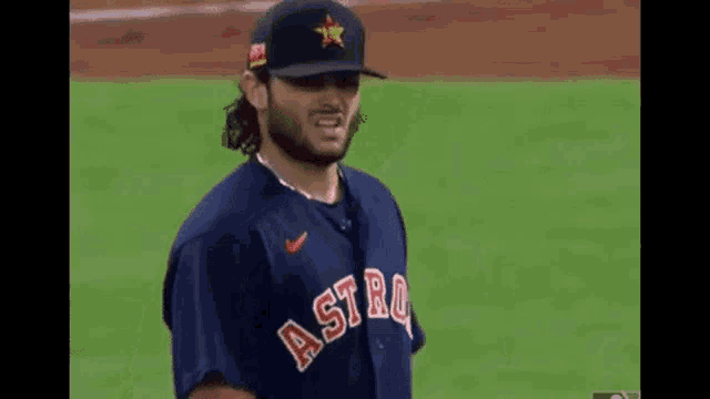 a baseball player wearing a blue jersey with the word astros on it is standing on a field .