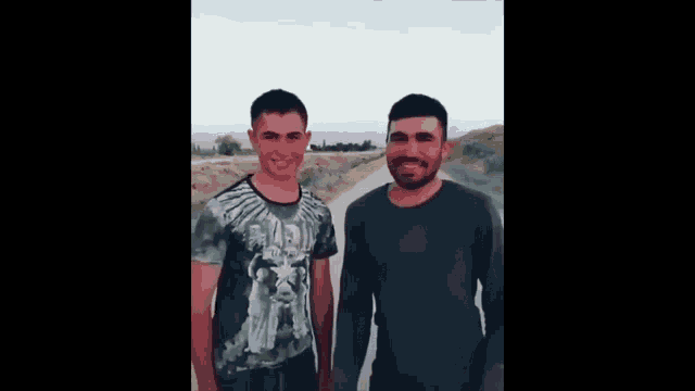 two men are standing next to each other on a dirt road and one of them is wearing a shirt that says justice league