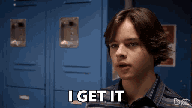 a young man says " i get it " in front of a row of blue lockers