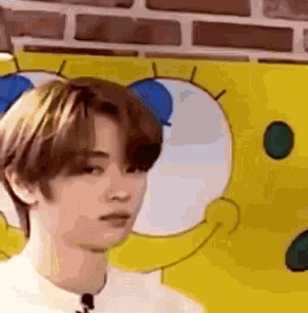 a young man is standing in front of a spongebob squarepants poster .