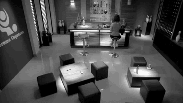 a woman sits at a bar in a room with a sign that says crema capecion
