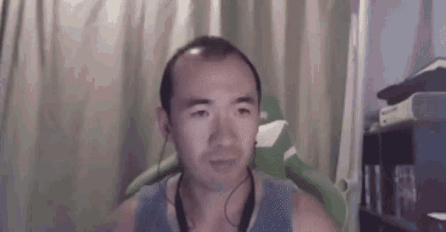 a man wearing headphones and a tank top is sitting in a chair .