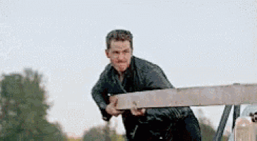 a man in a black shirt is holding a piece of wood .