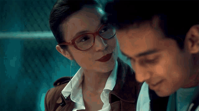 a woman with red glasses looks at a man
