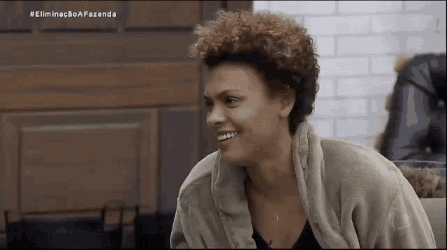 a woman with curly hair is smiling while wearing a bathrobe .