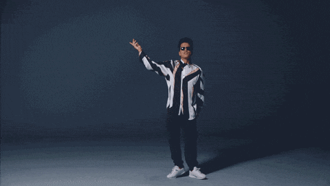a man in a suit is dancing in a dark room while holding a microphone