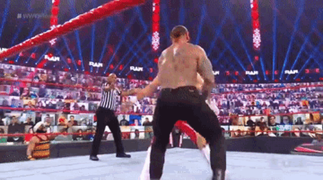 two men are wrestling in a wrestling ring with a referee in the background