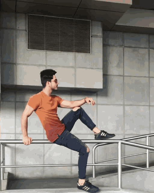 a young man is sitting on a railing with his leg up