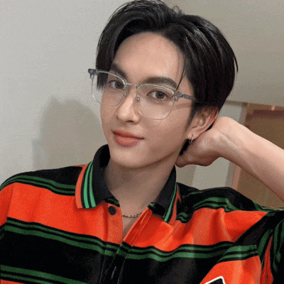 a young man wearing glasses and a striped shirt looks at the camera