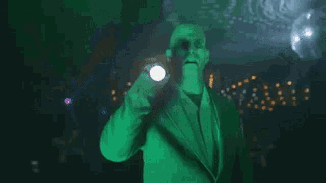 a man in a suit is holding a flashlight in front of a disco ball .