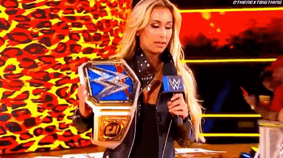 a woman is holding a wrestling championship belt in front of a microphone .