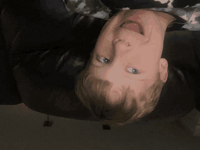 a young boy laying on his back with his tongue hanging out