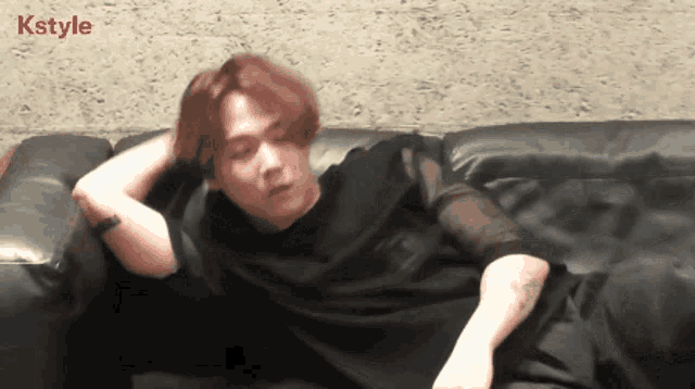a man laying on a couch with kstyle written on the bottom right