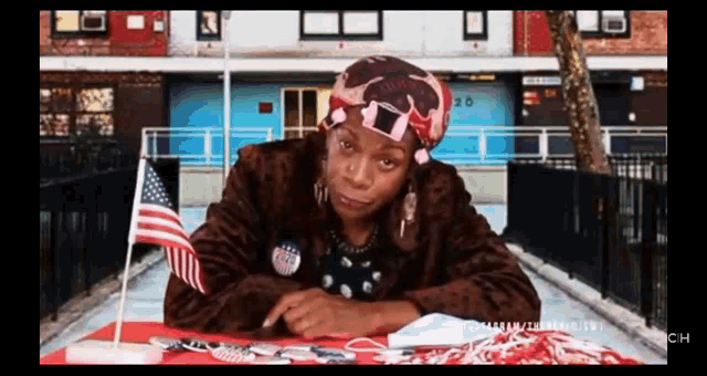 a woman is sitting at a table with an american flag
