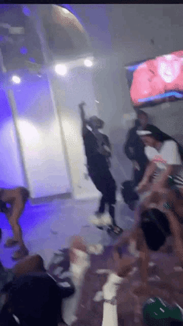 a group of people are dancing in a room with a purple light