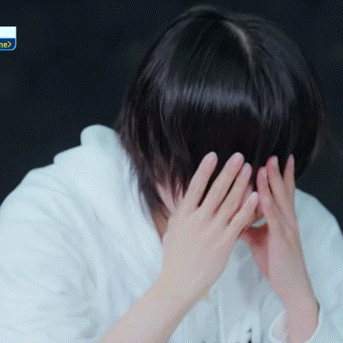 a person covering their face with their hands in front of a sign that says " ne "