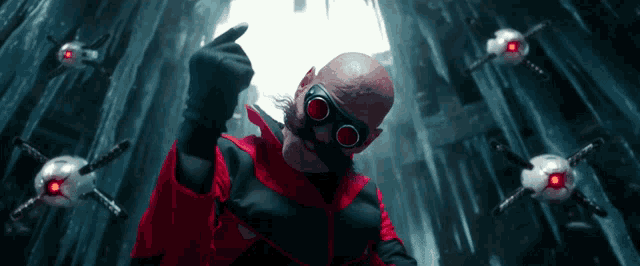 a bald man in a red and black superhero costume is surrounded by robots with red eyes