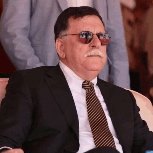a man with a mustache wearing sunglasses and a suit and tie