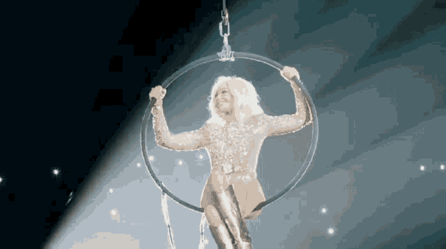 a woman is hanging upside down in an aerial hoop on a stage