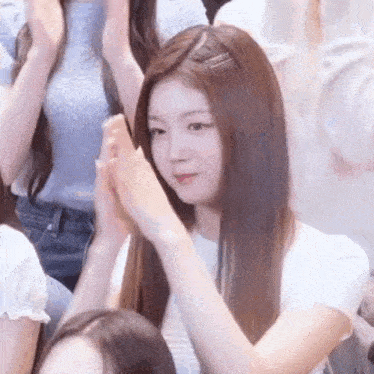 a woman with long hair is clapping her hands in a crowd of people .