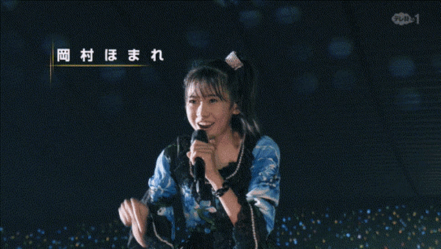 a woman singing into a microphone with japanese writing on the bottom