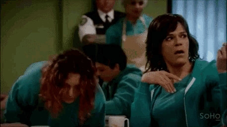 a group of women in green sweaters are sitting at a table with their hands on their hips .