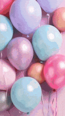 a bunch of different colored balloons are hanging from a string