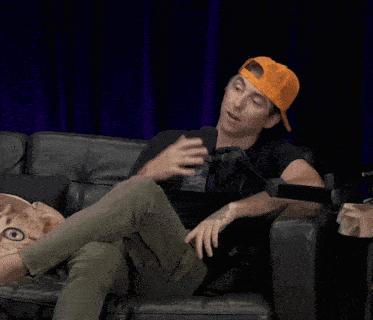 a man is sitting on a couch with a microphone that says ' comedy central ' on the front