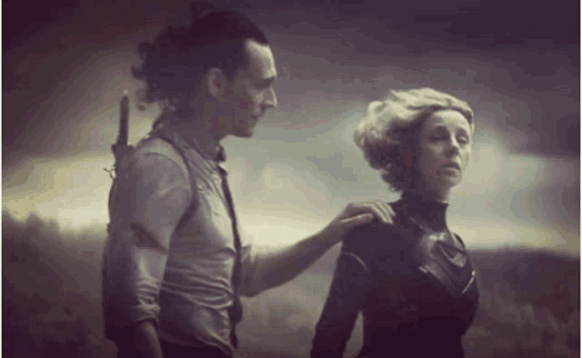 a man is putting his hand on a woman 's shoulder while they are standing next to each other .