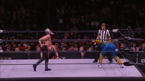 a man in a wrestling ring with a referee and a sign that says nbc