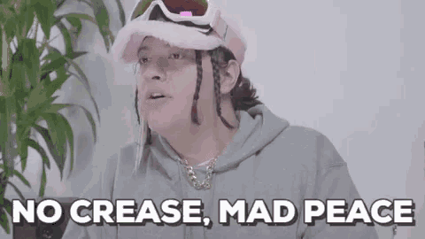 a woman wearing a pink hat and goggles is sitting in front of a plant and says no crease , mad peace .