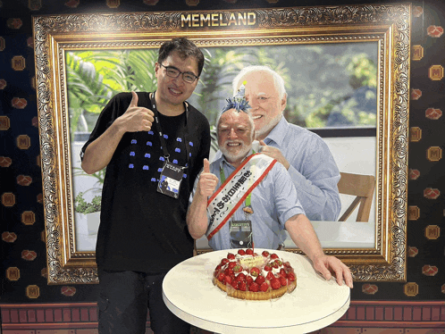 two men standing in front of a memeland poster