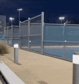 a tennis court is lit up at night with a fence around it